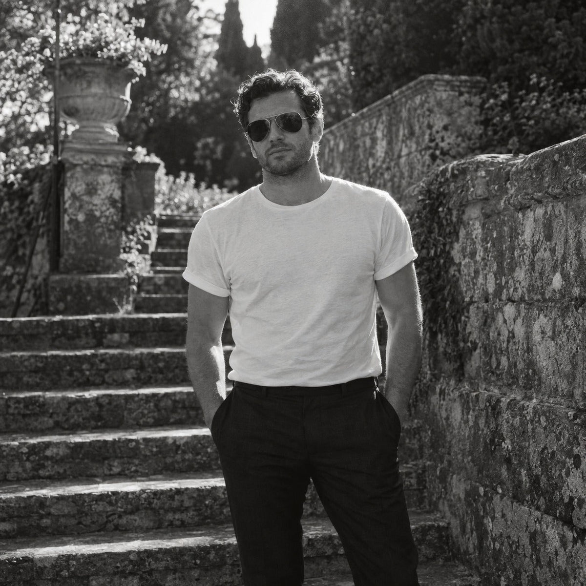 Man in a white t-shirt and dark trousers outdoors in spring light, black and white